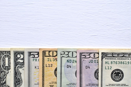 Dollar existing paper banknotes on painted white background