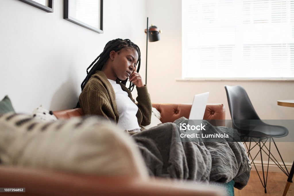 Shot of a young woman looking confused while using a laptop at home Technology has all the answers you need Women Stock Photo
