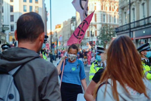 Extinction Rebellion Protestor with Flags. Protestor facing camera in crowded street protesting Covent Garden, London, UK extinction rebellion photos stock pictures, royalty-free photos & images