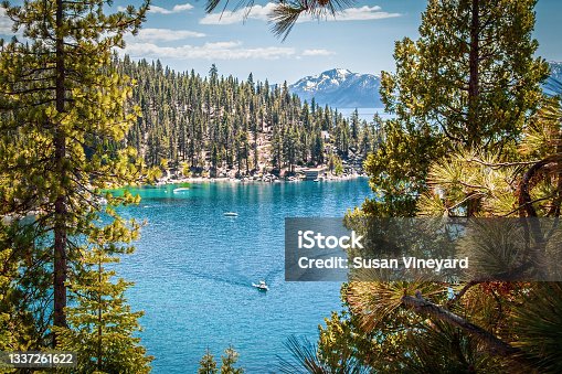 istock looking down through heavy forest onto Lake Tahoe USA and mountains in distance and boat creating wake in water down below. 1337261622