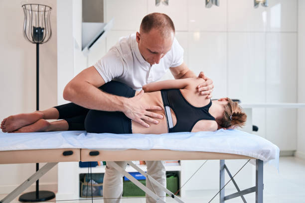 istock Charming female lying on massage table while doctor osteopath examining her body in medical center 1337261741