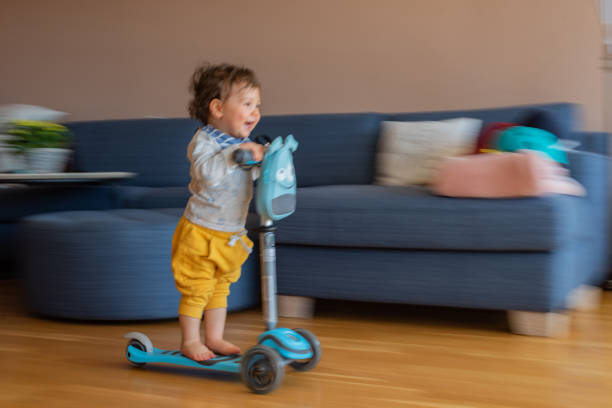 istock Boy riding scooter at home 1337261781