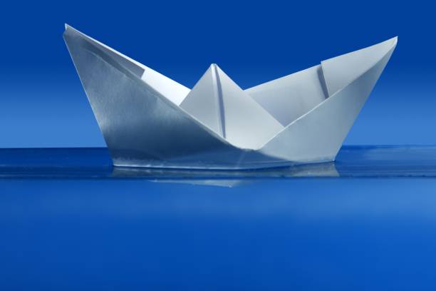 istock Paper boat floating over blue real water 1337263698