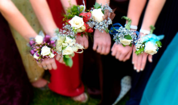 Girls holding arms out with corsage flowers for prom high school dance romance fun night party selective focus blur Girls holding arms out with corsage flowers for prom high school dance romance fun night party selective focus blur prom fashion stock pictures, royalty-free photos & images