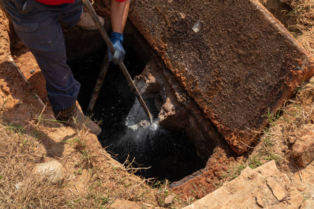 istock Man breaking apart a wastewater outlet in an old septic tank to bring it up to code 1337266339