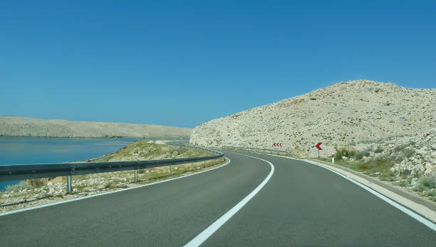 istock View on empty curved serpentine asphalt road with two lanes and white central strip between dry mountains at seaside - island Pag, Croatia 1337267787