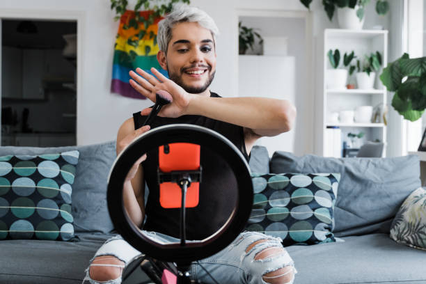 Drag queen streaming online make up tutorial with smartphone indoors at home - Lgbt, technology trendy concept - Focus in face