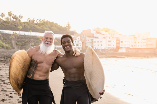 istock Multi generational surfer people having fun on the beach after surfing session - Multiracial men doing extreme sport outdoor 1337270556