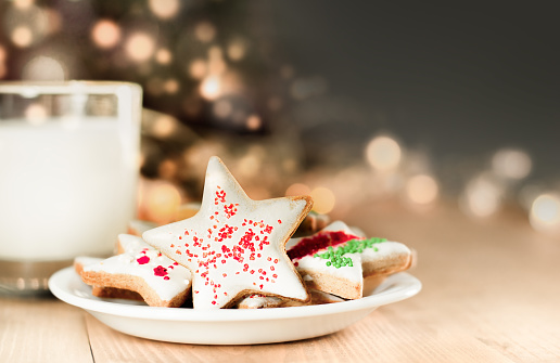 christmas cookies and milk for santa on a defocus christmas tree background