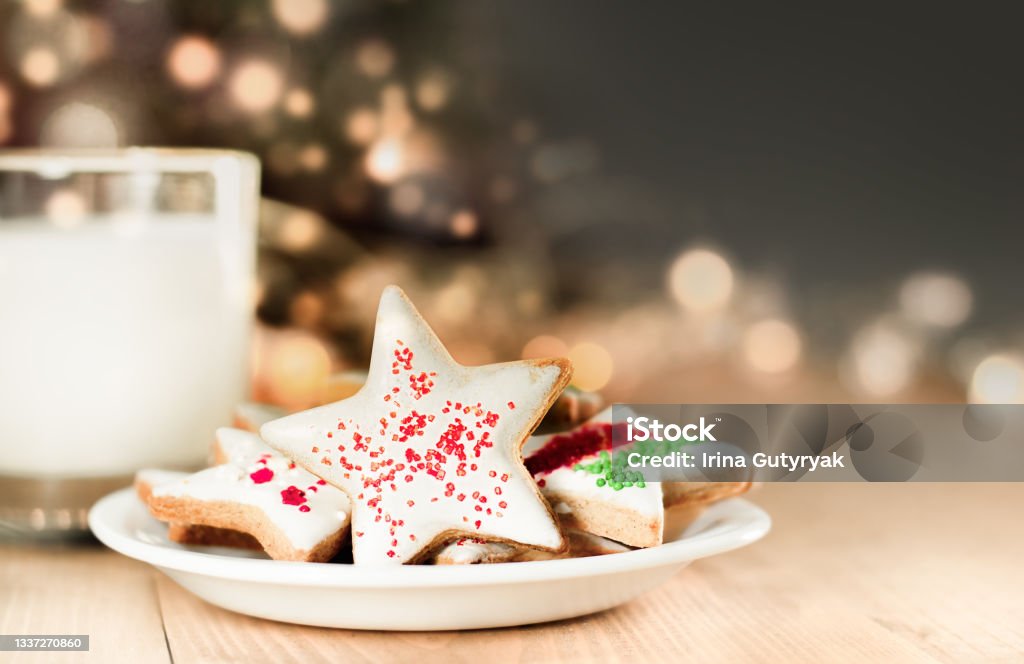 christmas cookies and milk christmas cookies and milk for santa on a defocus christmas tree background Christmas Stock Photo