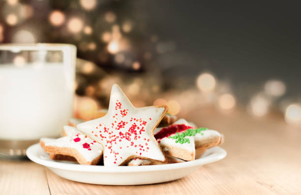 christmas cookies and milk christmas cookies and milk for santa on a defocus christmas tree background christmas cookies stock pictures, royalty-free photos & images