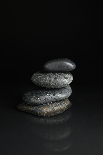 Stones in water on black background. Zen lifestyle