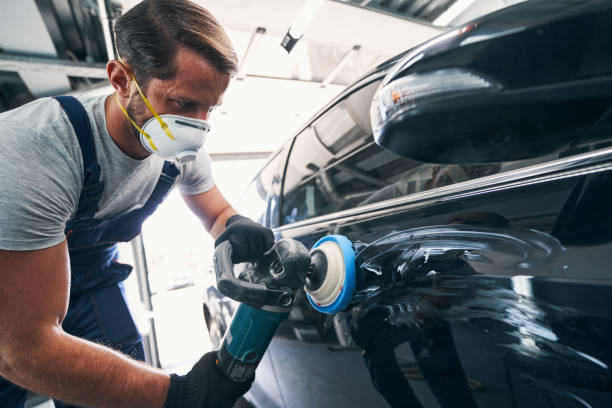 istock Repairman using polisher with blue pad on black automobile 1337272762
