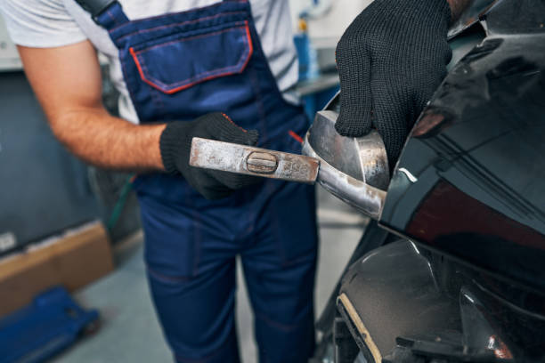 istock Auto mechanic peening car body surface with hammer 1337273413