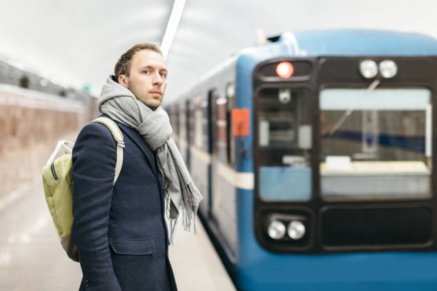 istock Cropped photo of handsome solid man in blue coat with a scarf and green backpack behind who missed train. In the background the train leaving platform. 1337274776