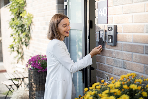 Woman attaches card to the electronic reader to access the apartment. Card entry, personal identification, keyless access, technologies in everyday life