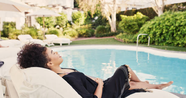 przycięte ujęcie atrakcyjnej młodej kobiety relaksującej się na leżaku przy hotelowym basenie - swimming pool luxury contemporary deck chair zdjęcia i obrazy z banku zdjęć