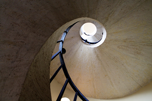 White spiral stairs rise from a white room