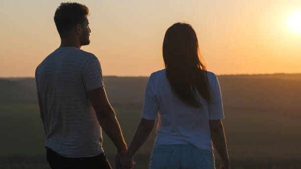 istock The romantic couple standing on mountain top on sunset background 1337278033