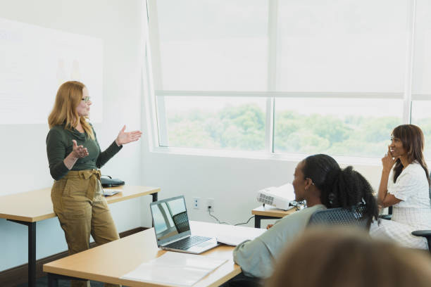 istock Using overhead projector, woman gestures as she teaches adult class 1337284983