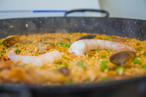 Fresh rice paella is cooking in the heat fire gas stove with seafood, shrimp, mussels, clam and pork meat