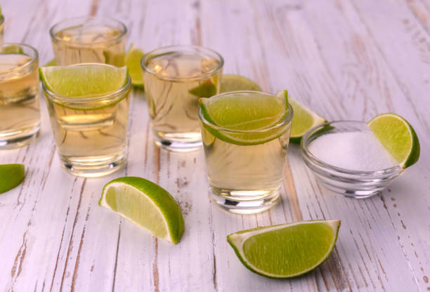 istock Small glasses with tequila on a white wooden background. 1337290170