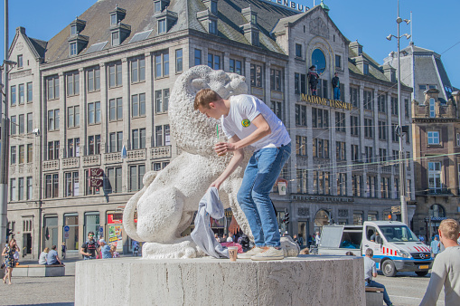 Tourist On A Lion Belonging To The Remembrance Of The Dead Statue At Amsterdam The Netherlands 6-5-2018