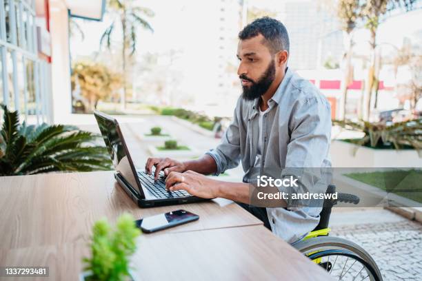 Wheelchair Man Working On The Computer In The Cafeteria Stock Photo - Download Image Now