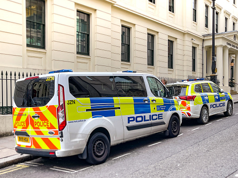 Two Metropolitan Police cars attending an incident in Tower Bridge Road, Southwark, in South East London. A cluster of police officers can be seen near the beginning of Tower Bridge, just up the road.