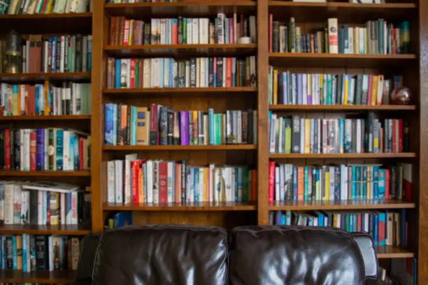 Photo of Wooden bookcase filled with blurred books in a UK home setting
