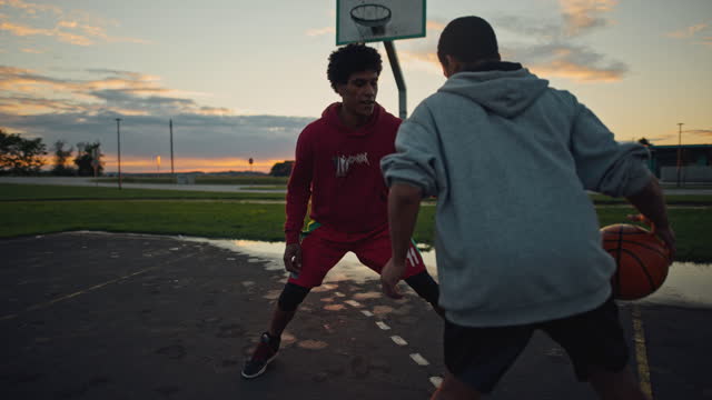 Slow motion shot of two young basketball players having fun playing basketball on the basketball court. Players dribbling the ball.