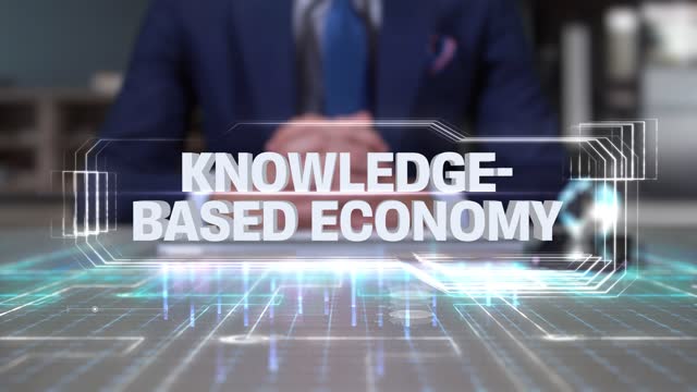 Businessman Writing on Hologram Table Economics Word- Knowledge-based economy