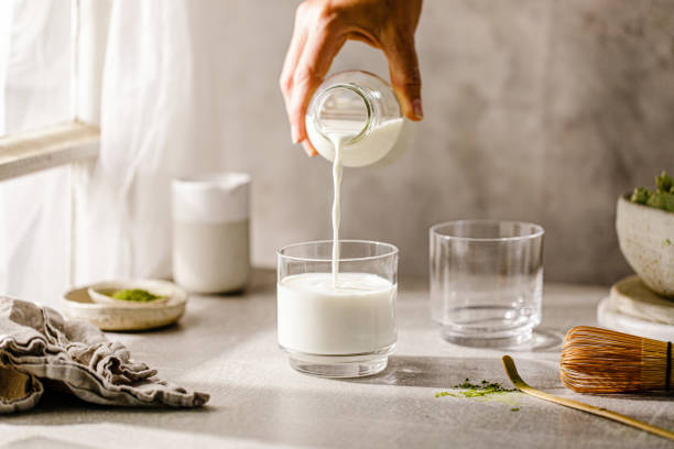 Hand pouring milk in glass from bottle