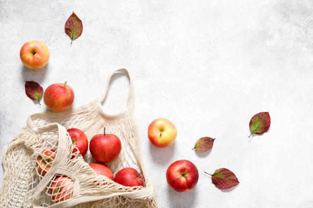 Red ripe apples in shopping bag on white background. Autumn apple flat lay, top view, copy space. Autumn harvest, apple cooking concept stock photo