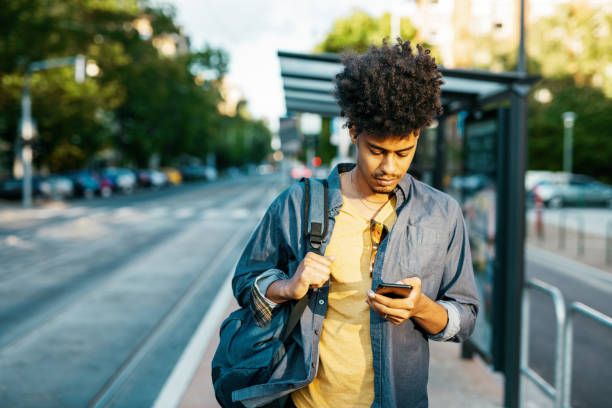 istock Mixed race millennial man using mobile phone while waiting for bus 1337309572