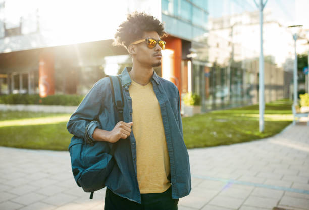 istock Portrait of mixed race millennial man in downtown with backpack 1337310184