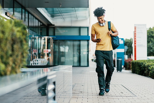 Photo of young mixed race male in downtown, going to work or back from work, drinking coffee, using public transport or sipping coffee