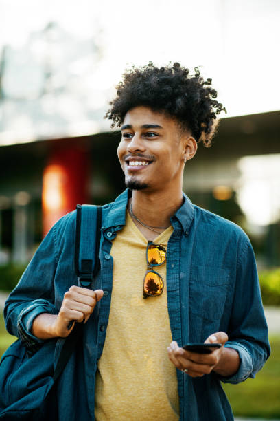 istock Mixed race millennial man in downtown, using mobile phone and smiling 1337310492
