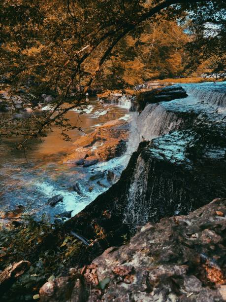 istock Waterfall surrounded by orange and amber leaves and foliage 1337311436