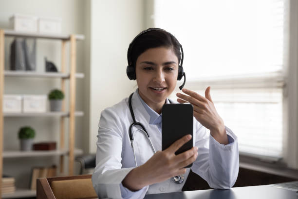 happy young indian doctor holding mobile video call meeting. - médico geral imagens e fotografias de stock