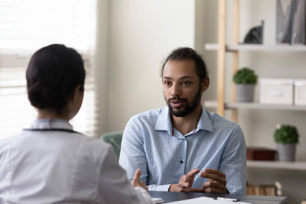 junger afroamerikanischer patient, der mit dem arzt über die behandlung von krankheiten spricht. - asian ethnicity doctor patient healthcare and medicine stock-fotos und bilder