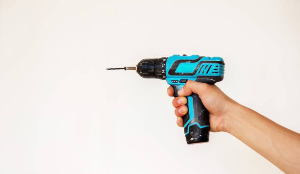 istock Hand with cordless screwdriver and drill isolated on white background. Twists screws into the board. 1337312858