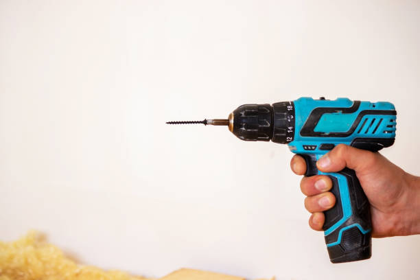 istock Hand with cordless screwdriver and drill isolated on white background. Twists screws into the board. 1337312860