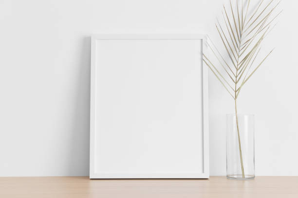 istock White frame mockup with a palm leaf on the wooden table. 1337318118