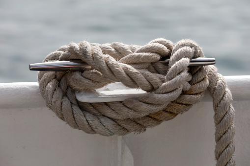Sailor coiling rope on sailboat. Model released.