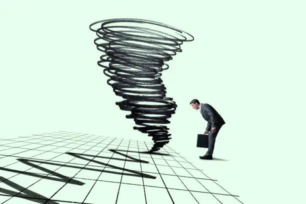 A man looks down as a tornado swirls around the financial chart that he stands on.