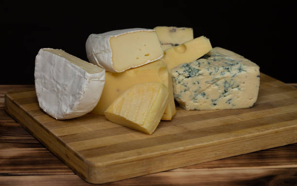 istock Different types of cheese on a rustic wooden cutting board on a dark background. 1337327133