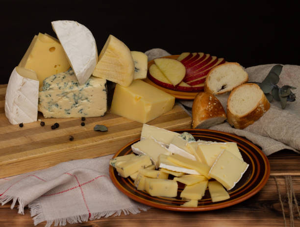istock Different types of cheese on a rustic wooden cutting board on a dark background. 1337327140
