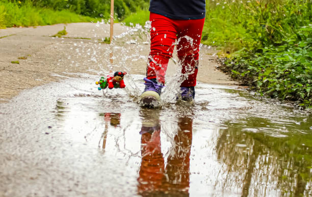 Child jumps into puddle with sliding animal in hand