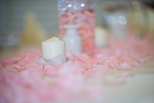 White tea light candle surrouned by pink flower pedals at wedding reception table